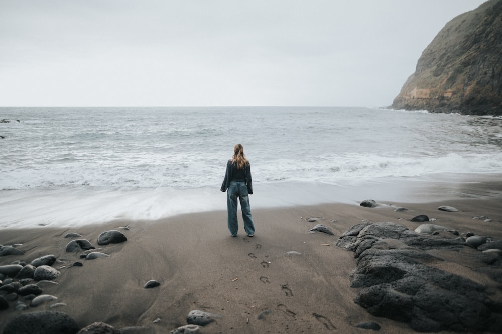 a woman standing on a beach next to the ocean