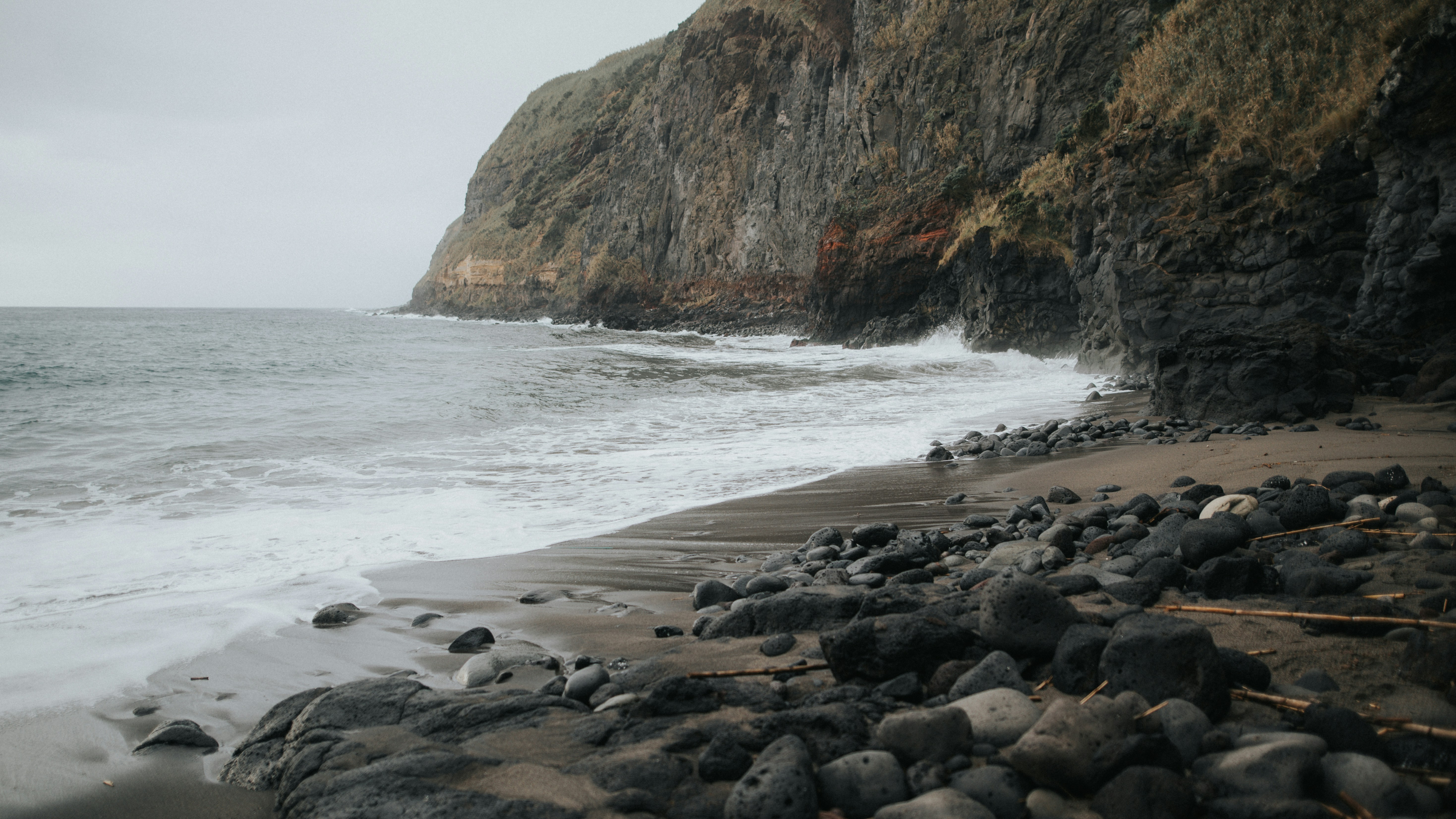 a rocky beach next to a rocky cliff, 