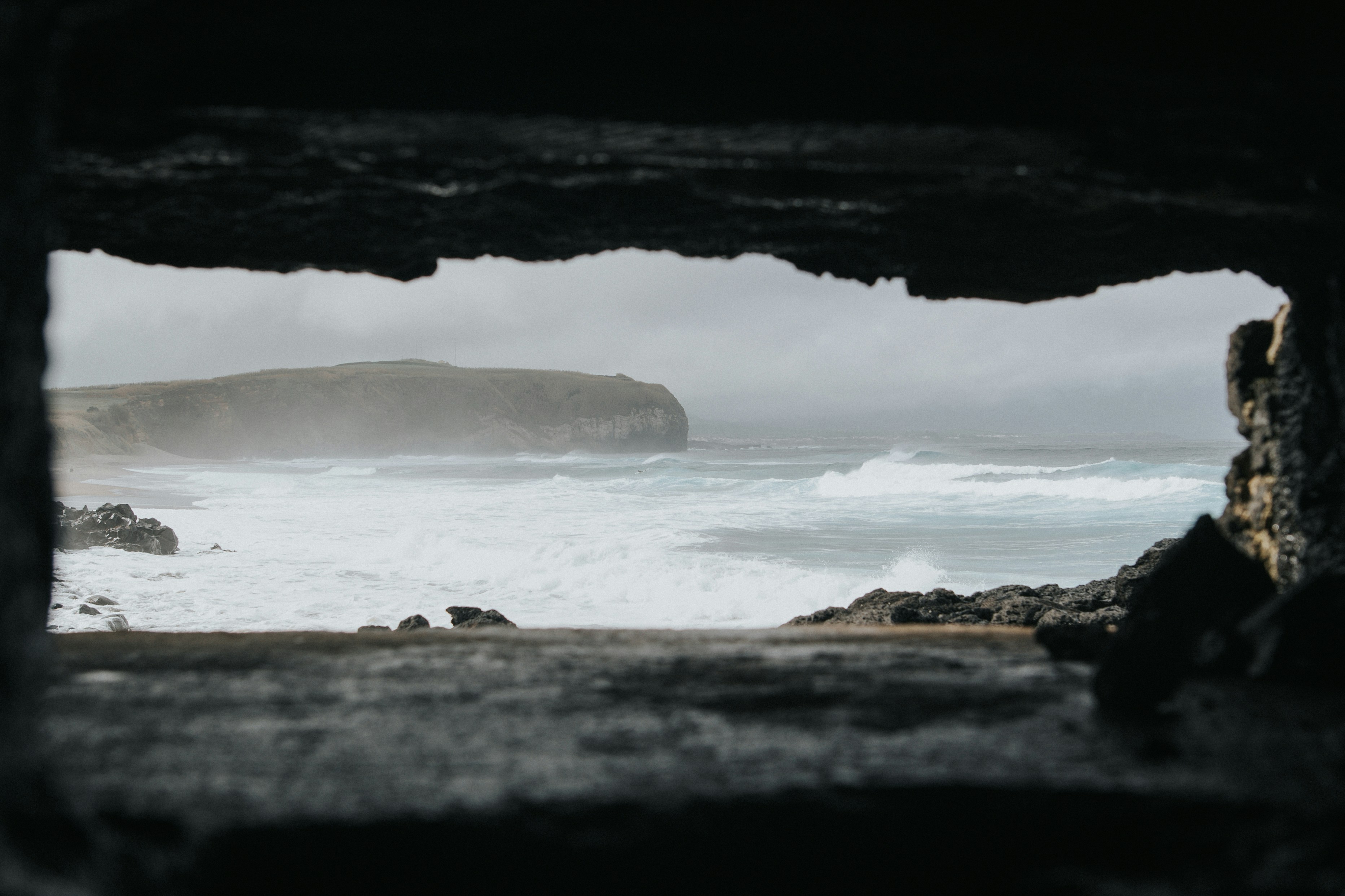 a view of a body of water from inside a cave, 