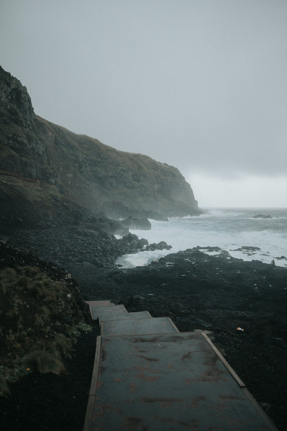 a path leading to the ocean on a foggy day