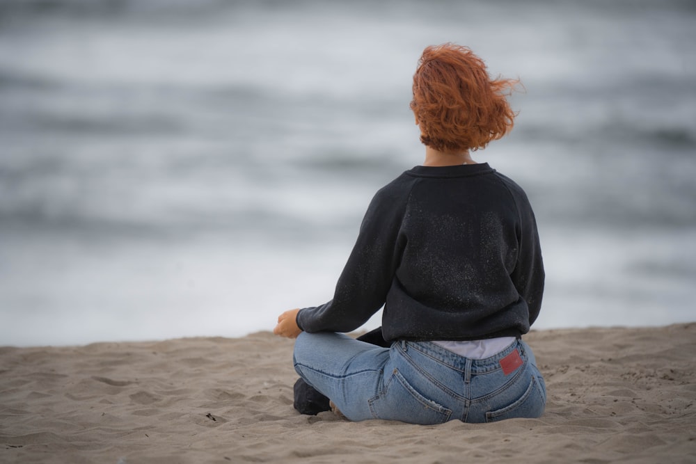 a woman sitting in the sand on the beach