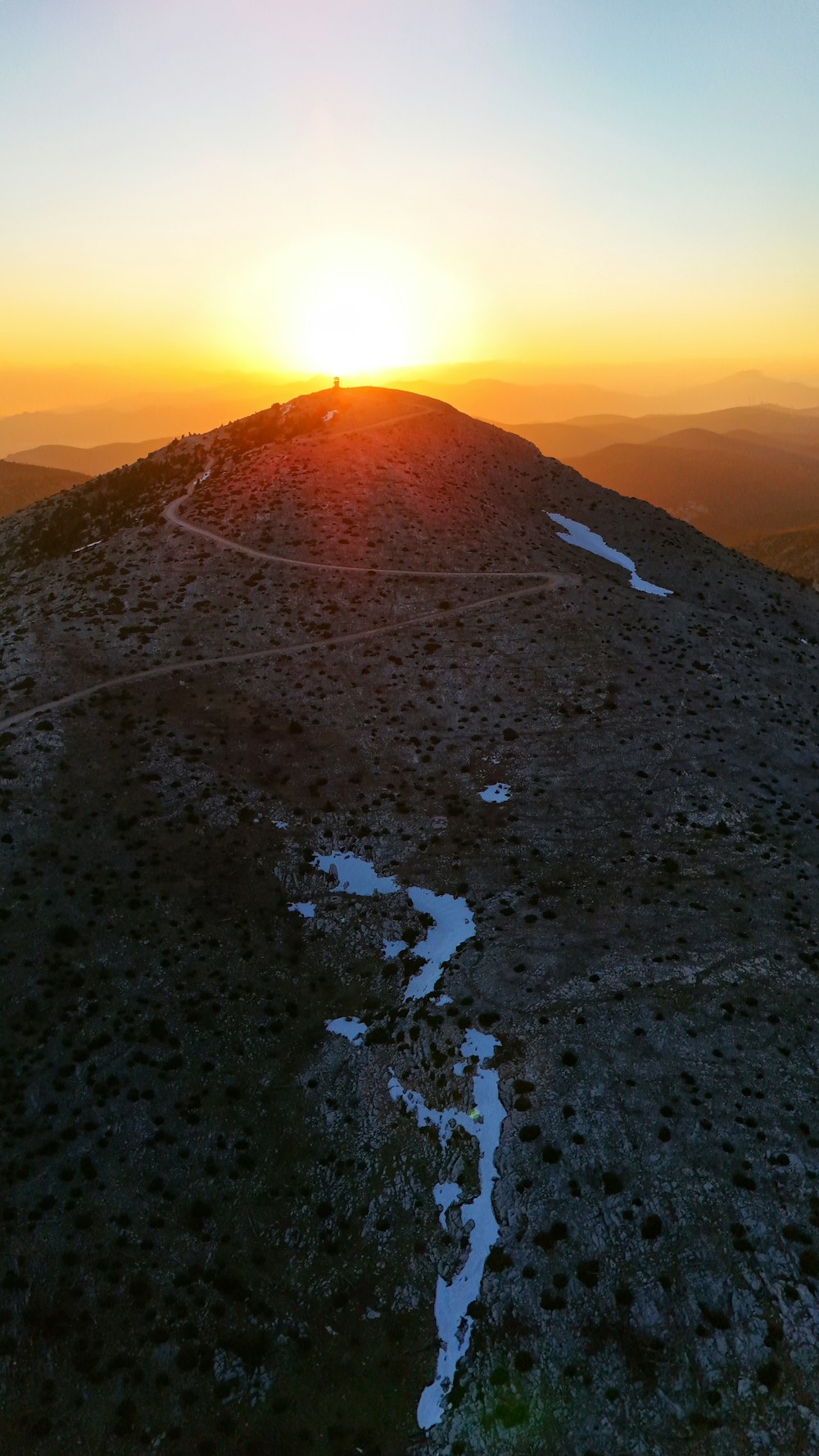 the sun is setting on the top of a mountain