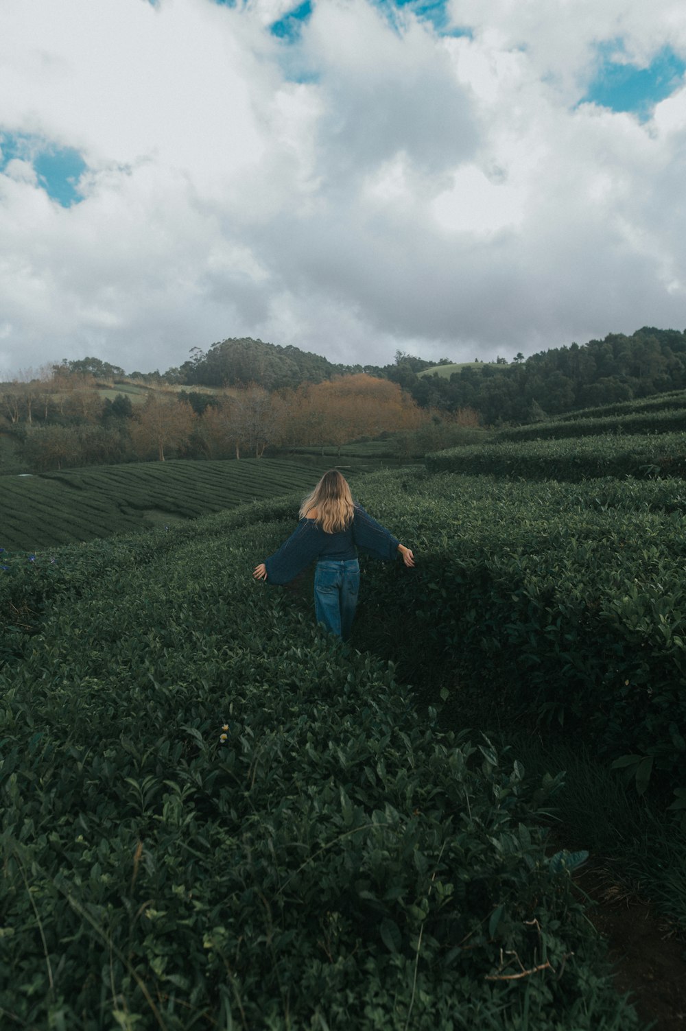 a woman walking through a lush green field