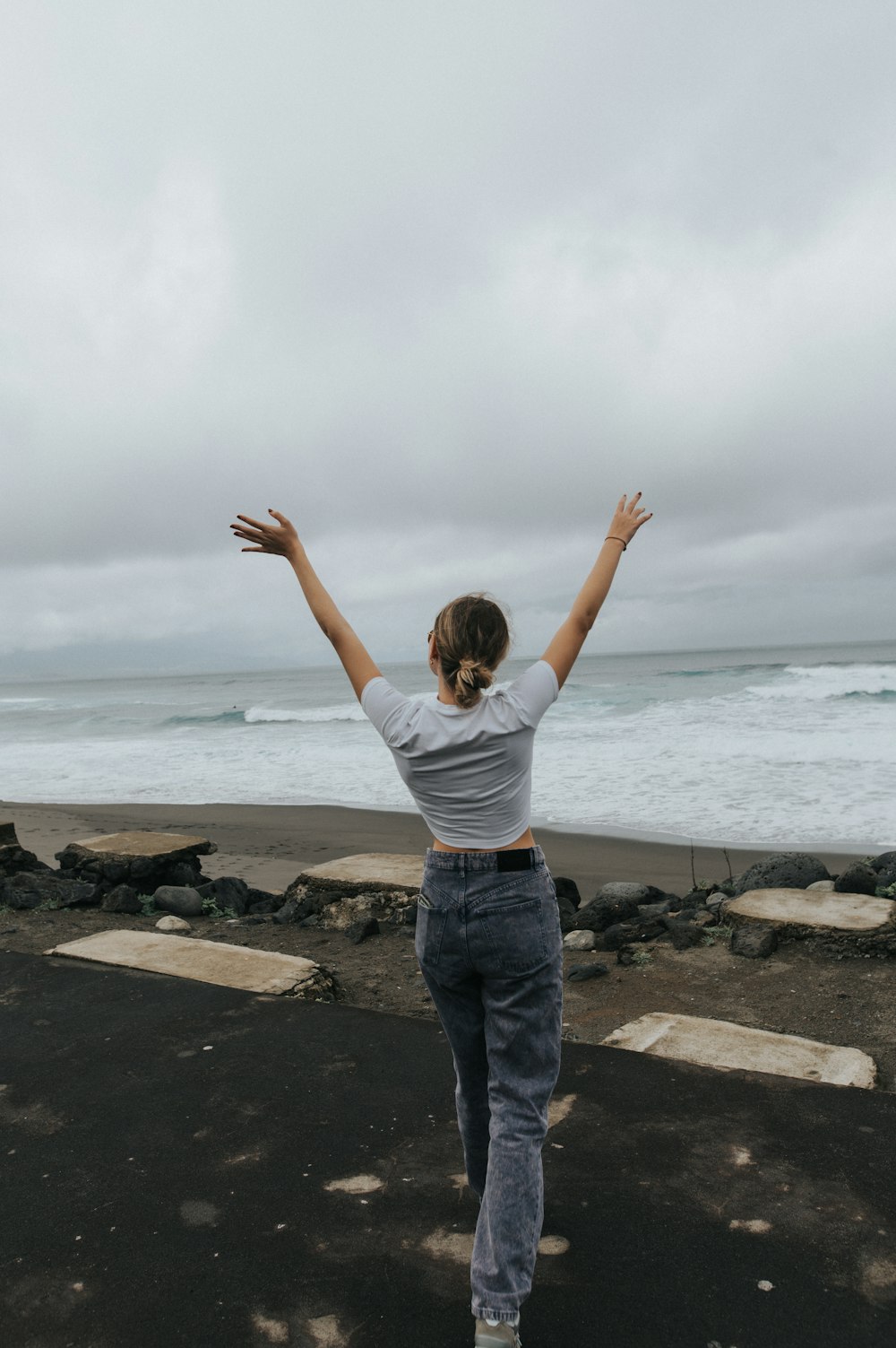 a woman standing on a beach with her arms outstretched