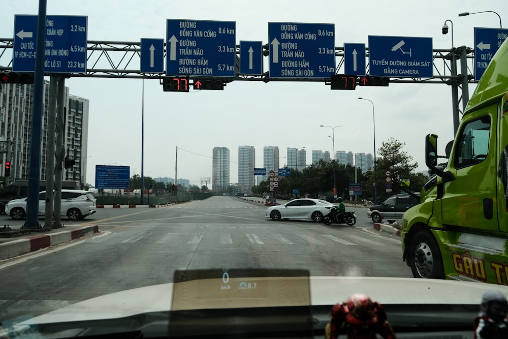 a green truck driving down a street next to tall buildings