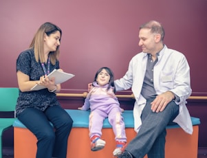 a woman and a man sitting on a bench with a little girl
