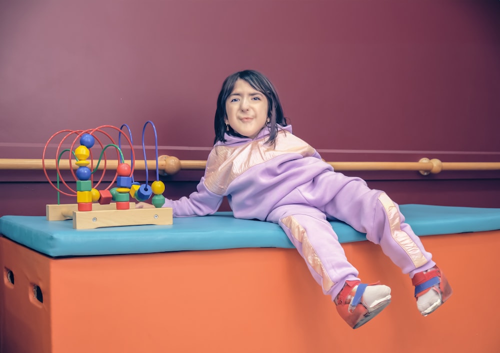 a little girl sitting on top of a blue bench