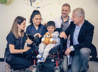 a group of people standing around a baby in a wheel chair