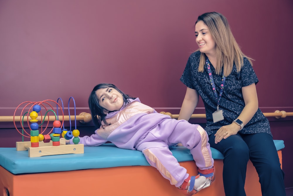 a woman sitting next to a little girl on a bench