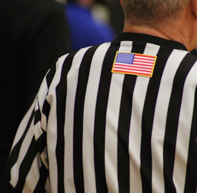 a man in a referee's uniform with an american flag patch on his back