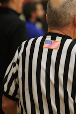 a man in a referee's uniform with an american flag patch on his back