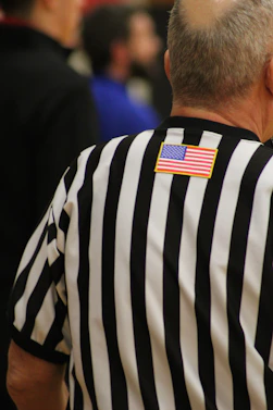 a man in a referee's uniform with an american flag patch on his back