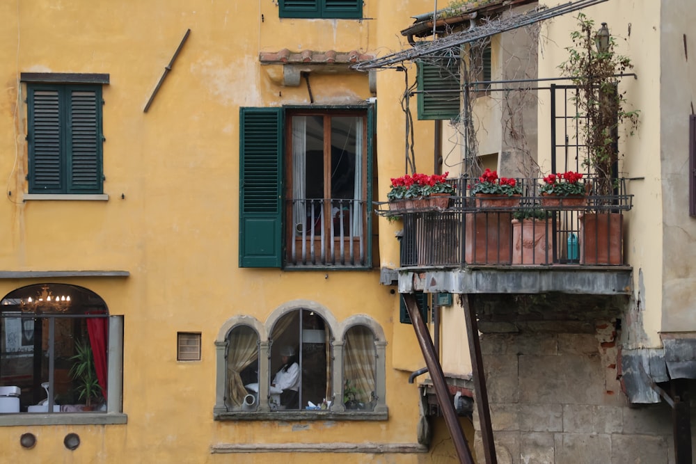 a yellow building with green shutters and a balcony