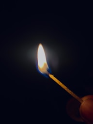 a lit matchstick in the dark with a lit match
