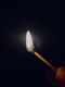 a lit matchstick in the dark with a lit match