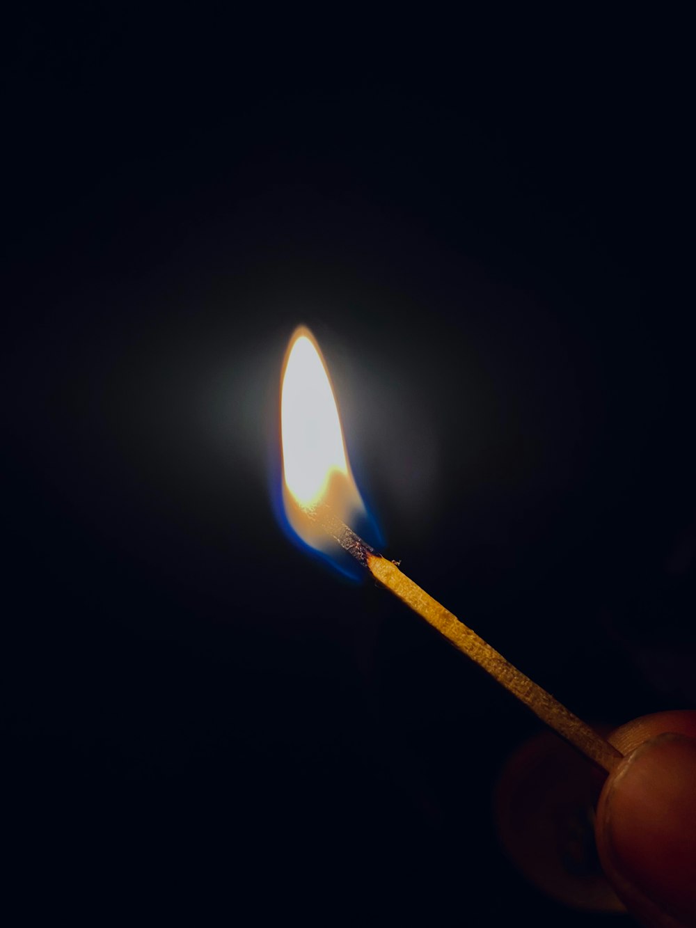 a lit matchstick in the dark with a lit match