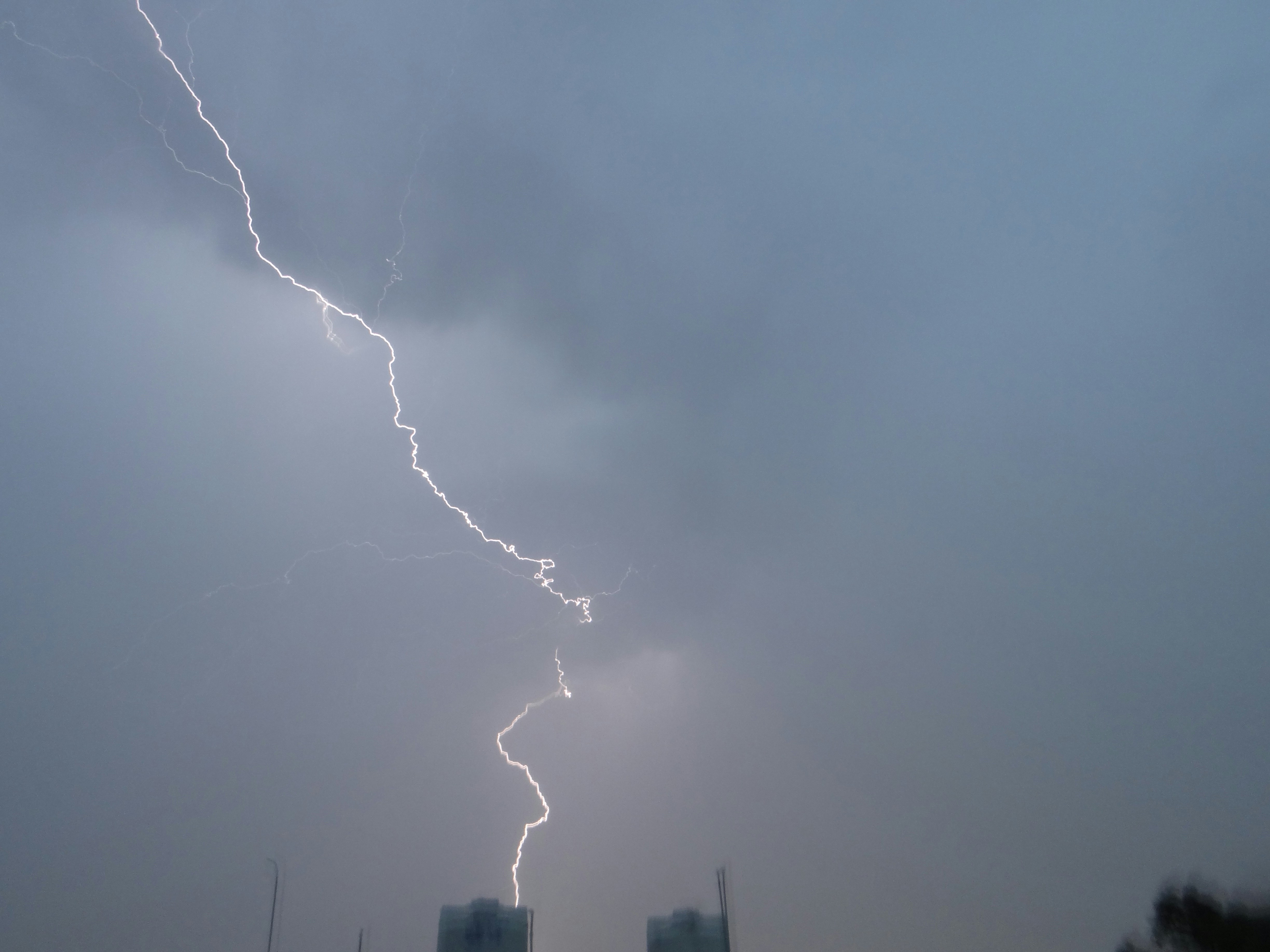 A lightning bolt is seen in the sky over a city photo – Free Grey Image ...