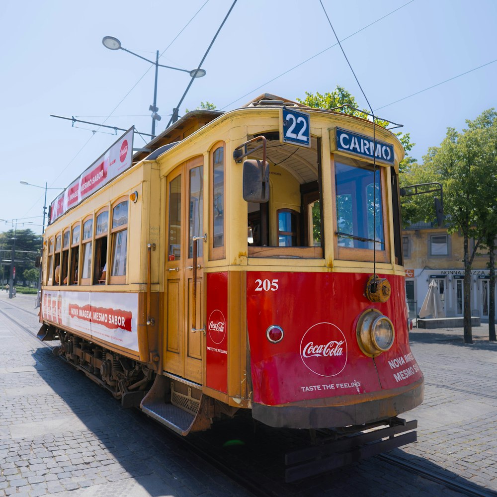 a red and yellow trolley car traveling down a street