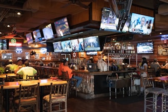 a group of people sitting at a bar watching tvs