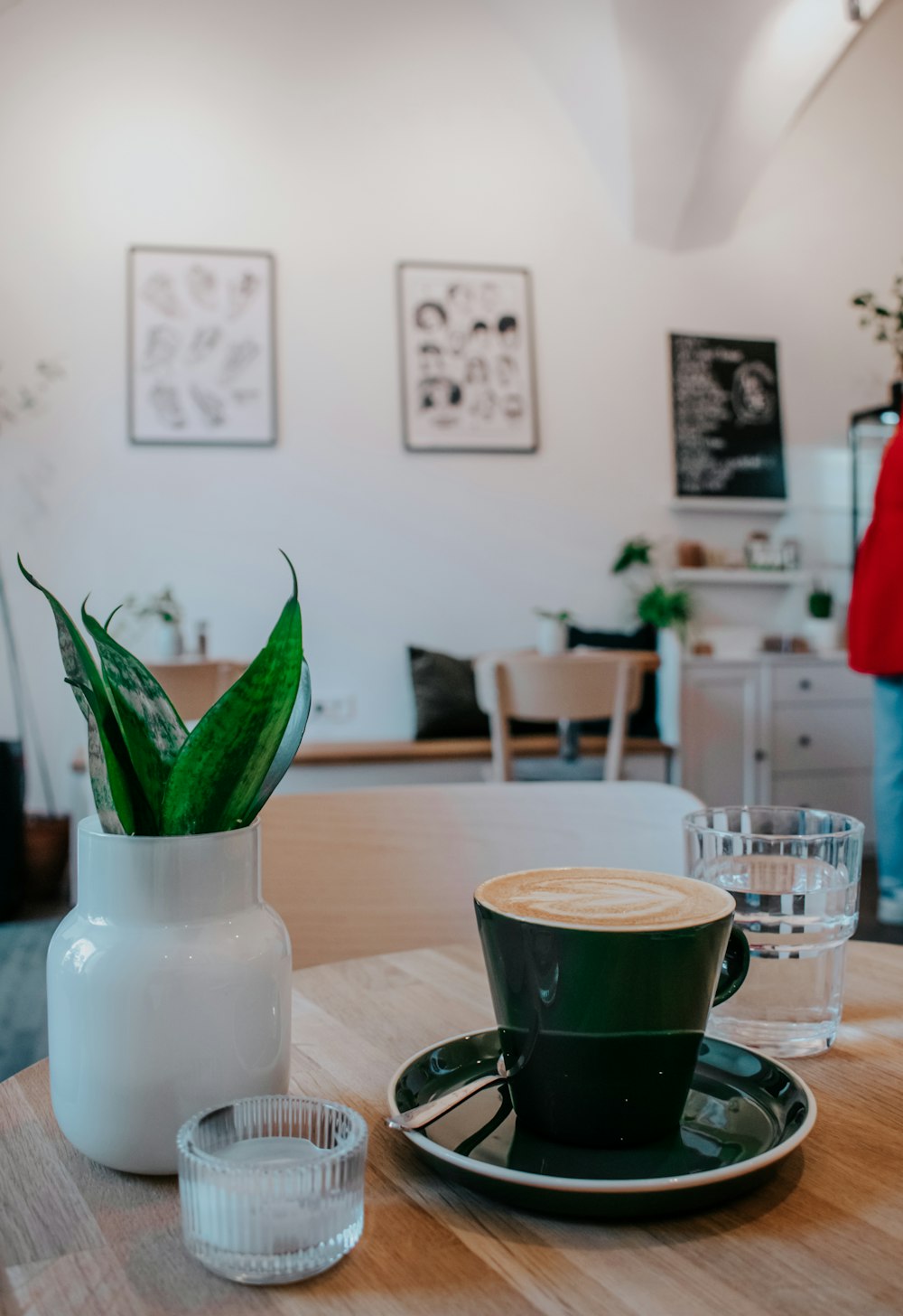 a table with a cup of coffee and a plant in a vase