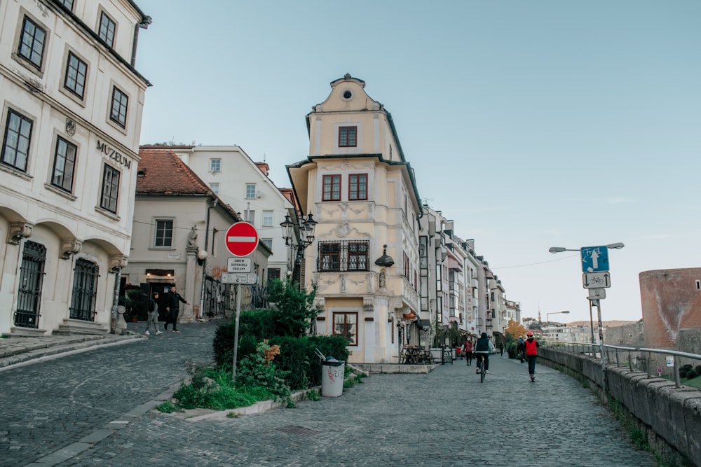 people walking down a cobblestone street in a european city