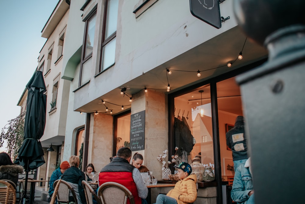 a group of people sitting at a table outside of a restaurant