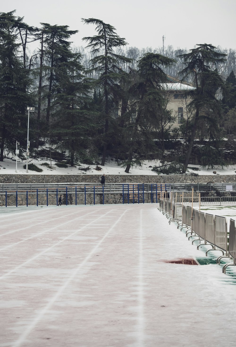 a person is walking in the snow near a fence