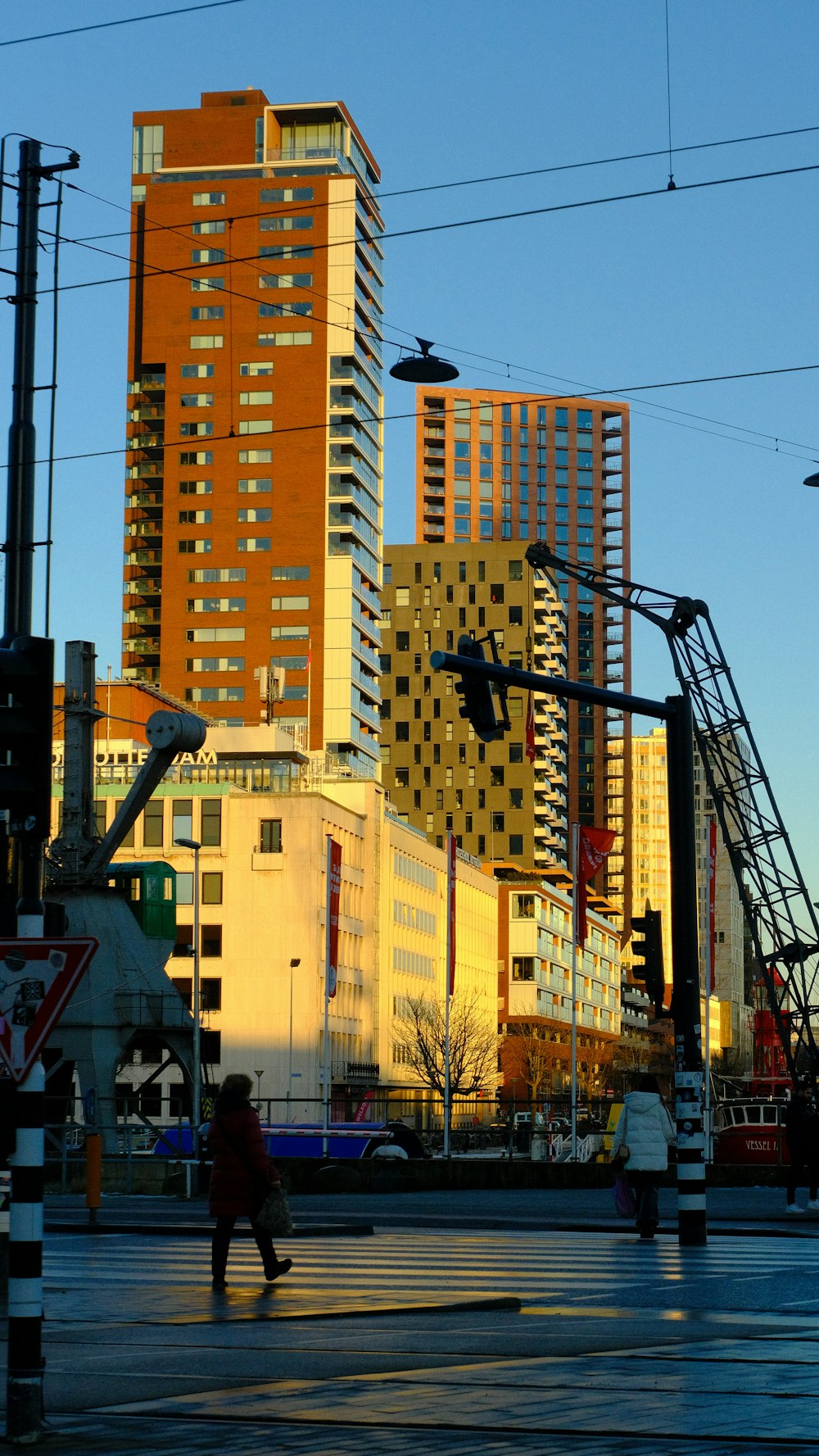 a couple of people walking across a street next to tall buildings