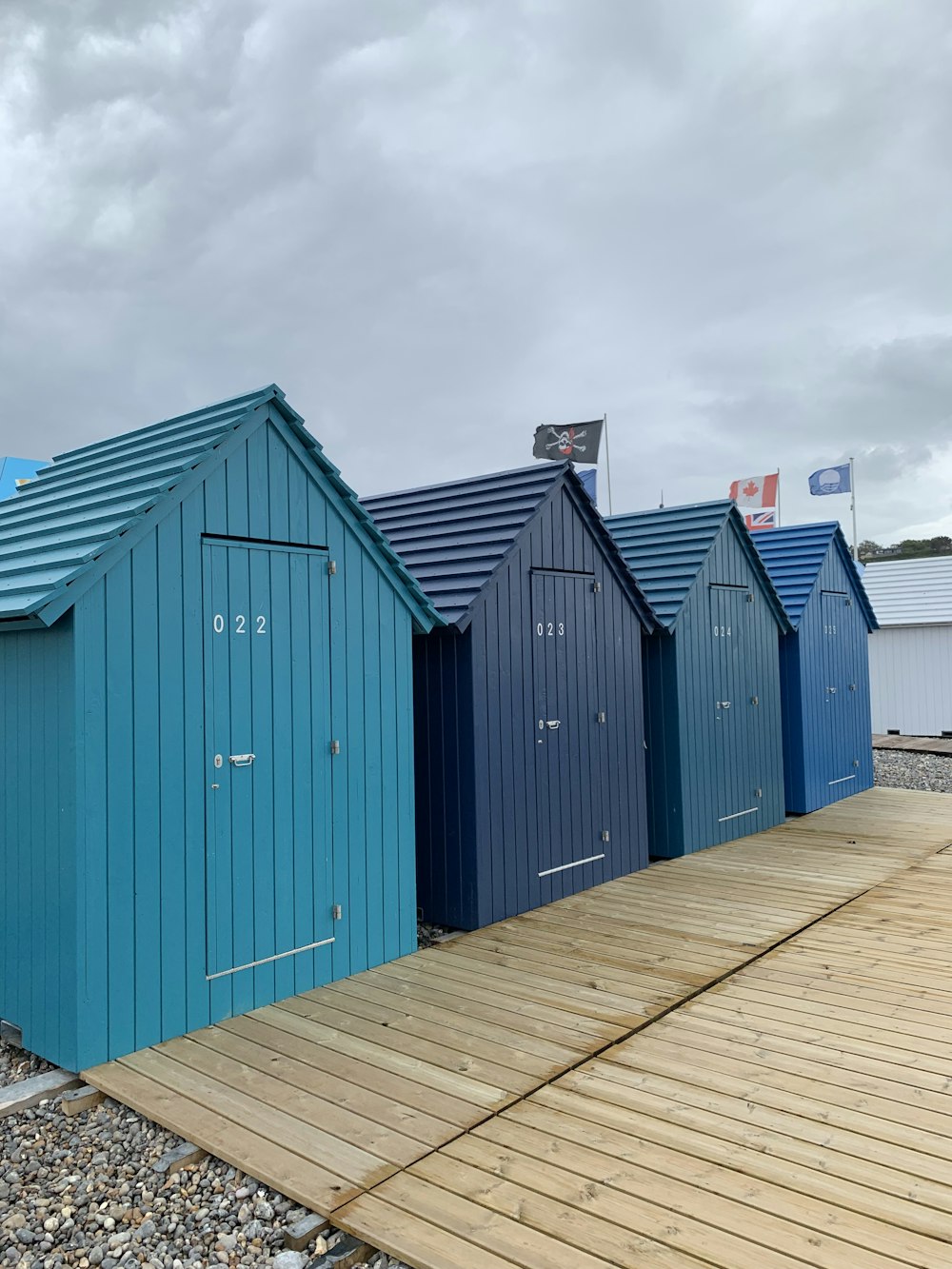 a row of beach huts sitting on top of a wooden pier