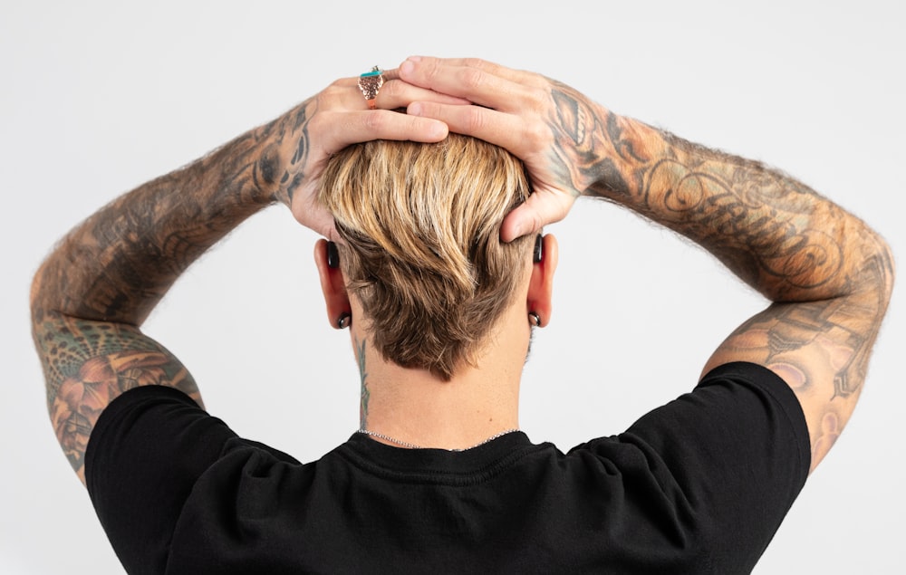 a man with tattoos covering his face and hands behind his head