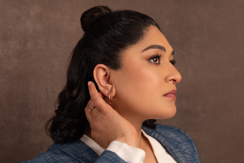 a woman wearing a suit and earrings looking off to the side