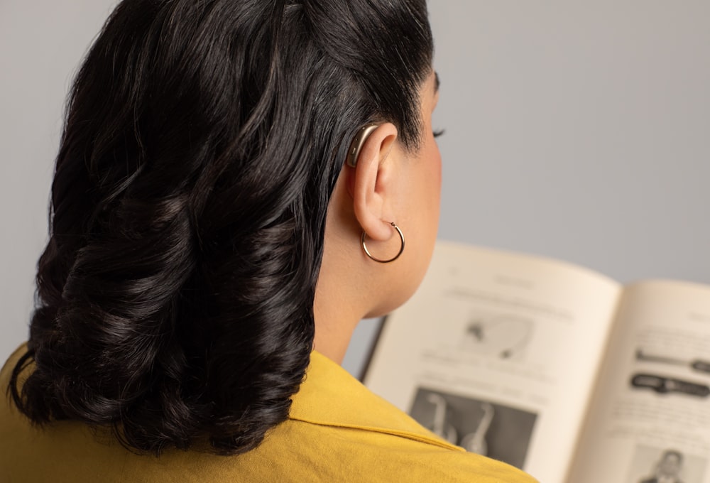 a woman reading a book with a pair of earrings on her ear