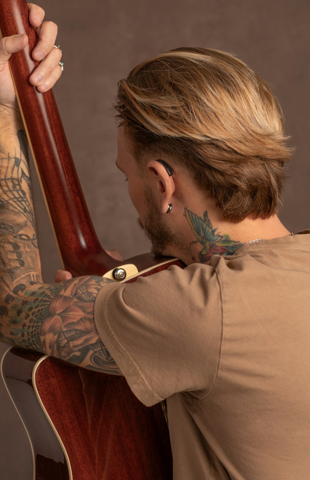 a man with a tattoo on his arm holding a guitar