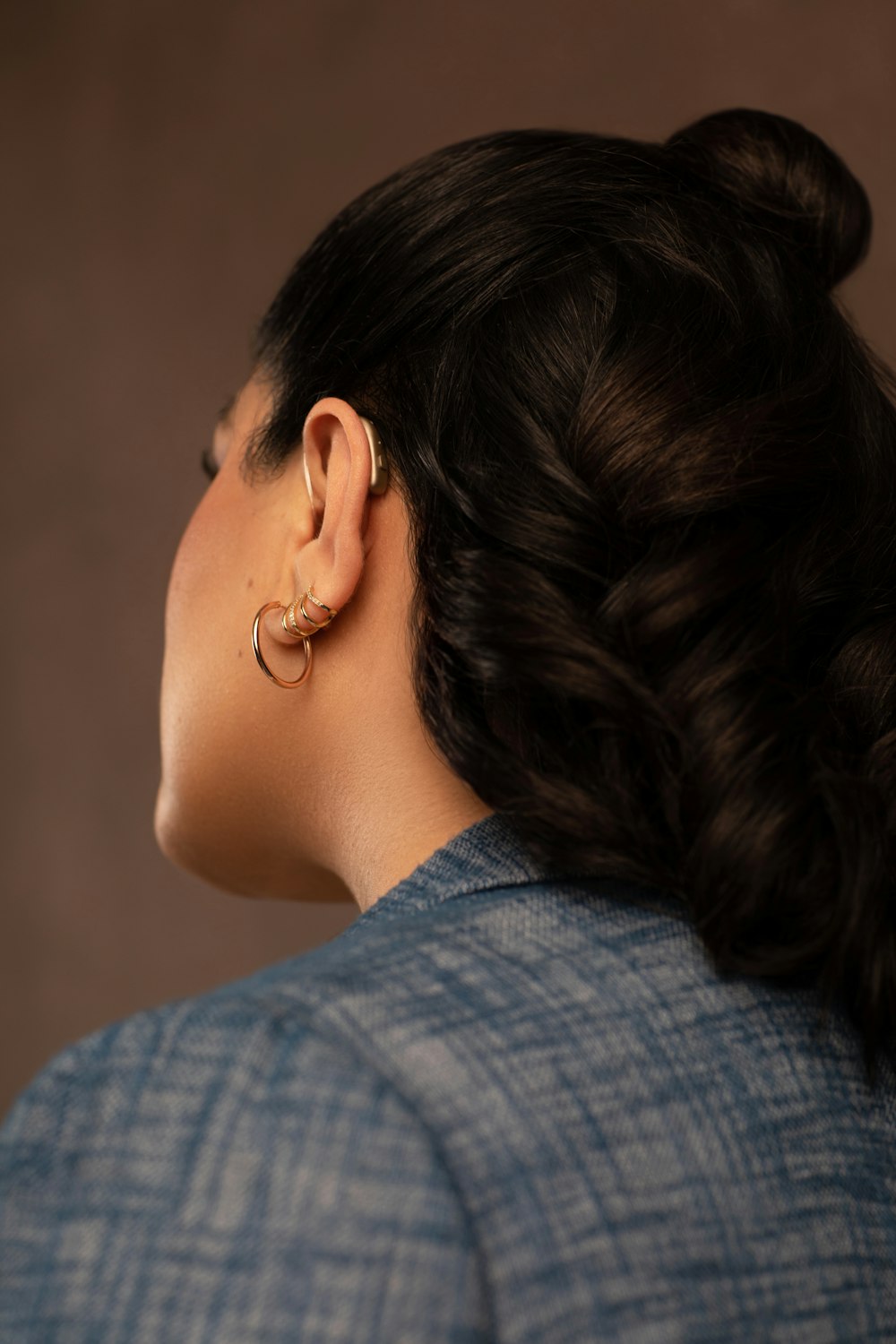 a woman wearing a blue jacket and a pair of earrings