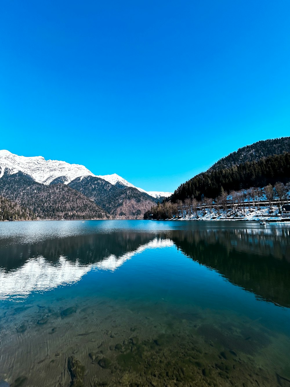 a lake surrounded by mountains and snow covered mountains