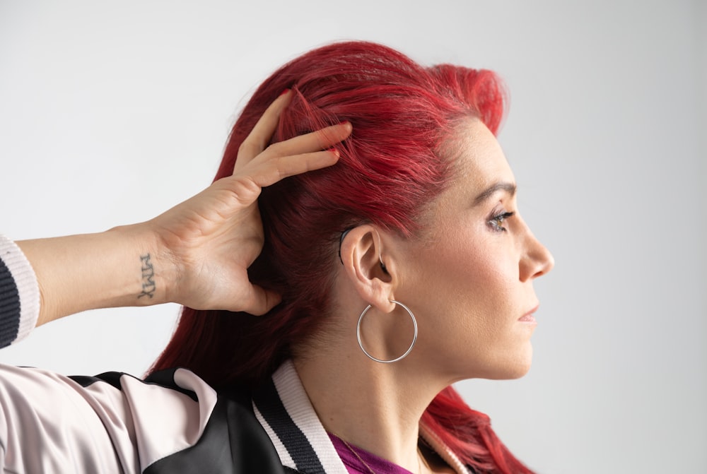 a woman with red hair is putting her hair in a ponytail