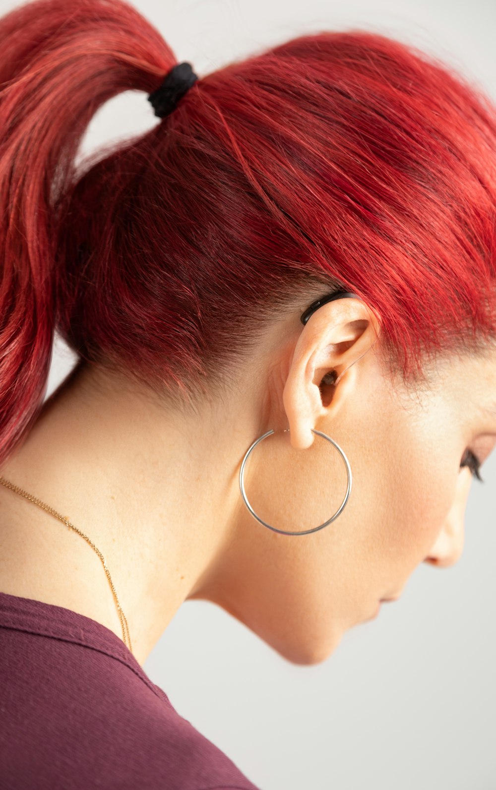 a woman with red hair wearing a pair of hoop earrings
