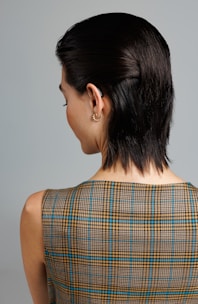 a woman with a short black hair wearing a plaid dress