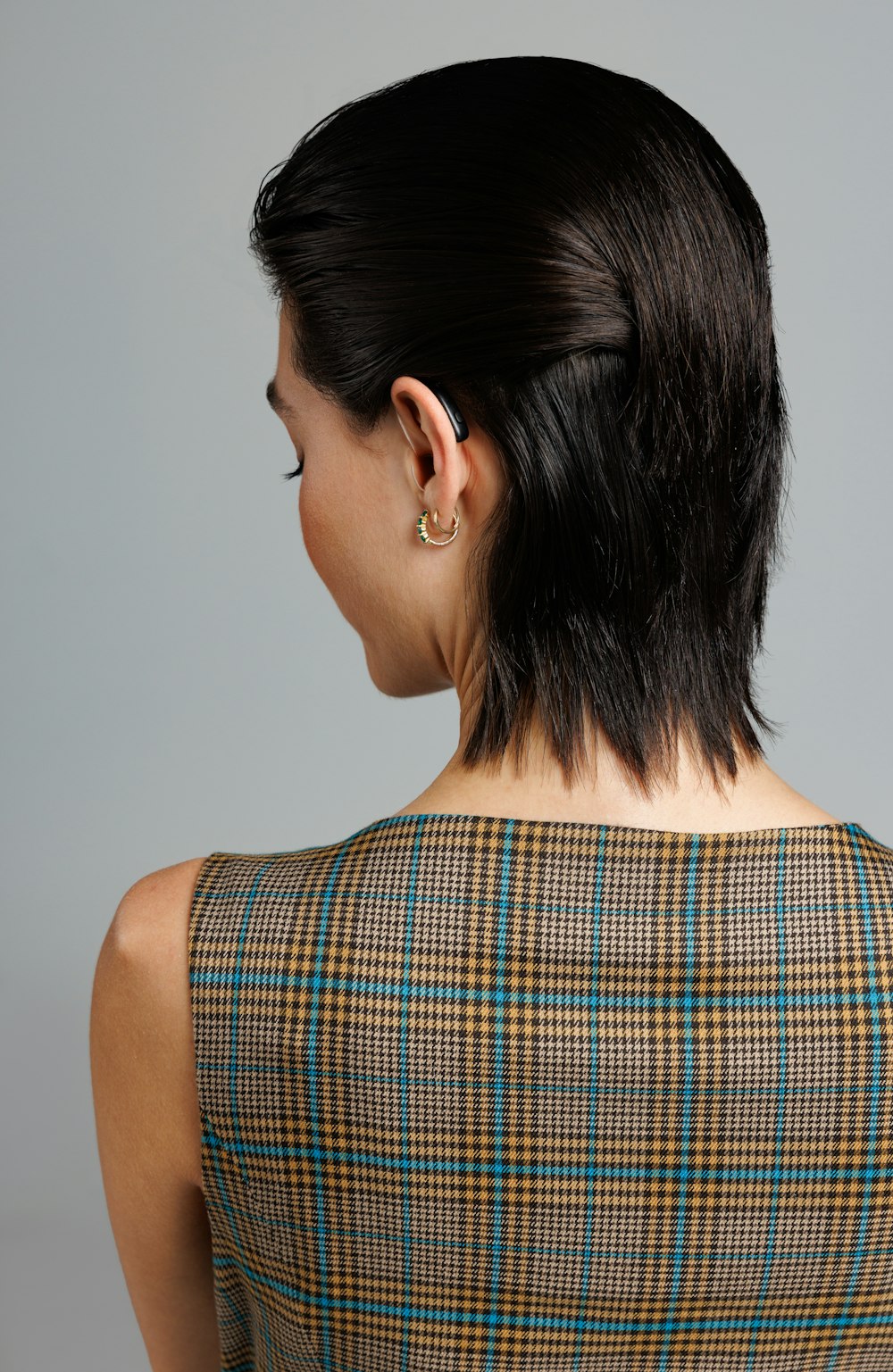 a woman with a short black hair wearing a plaid dress