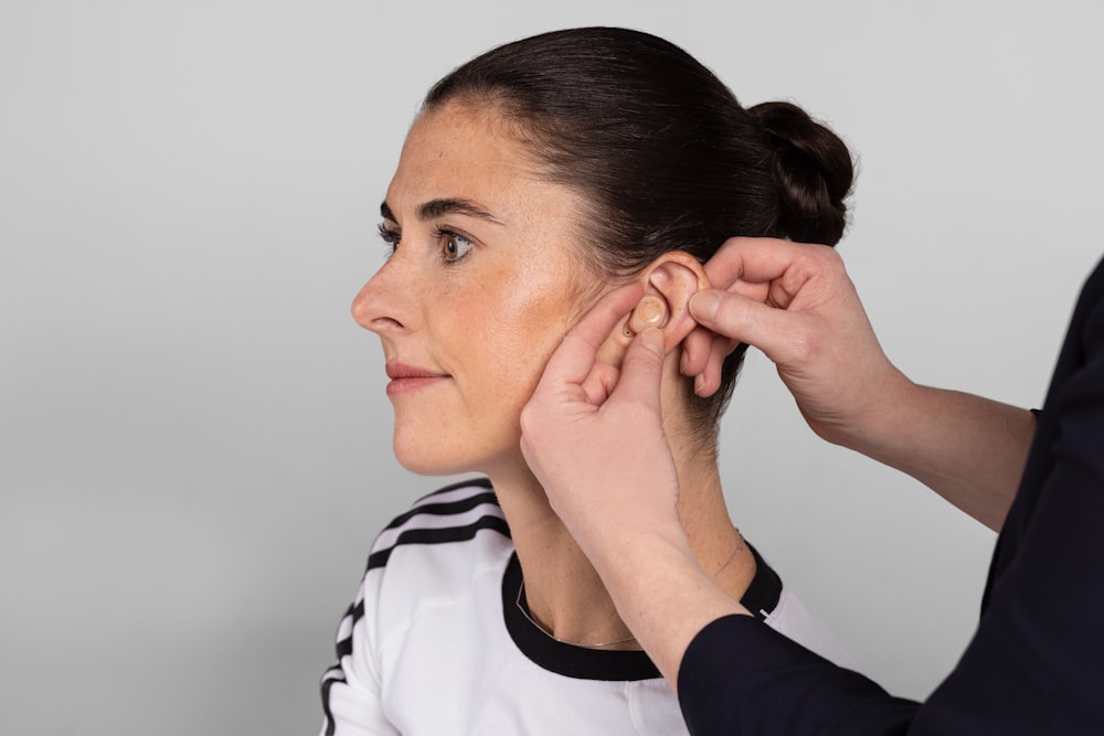 a woman is putting a pair of earplugs on her ear