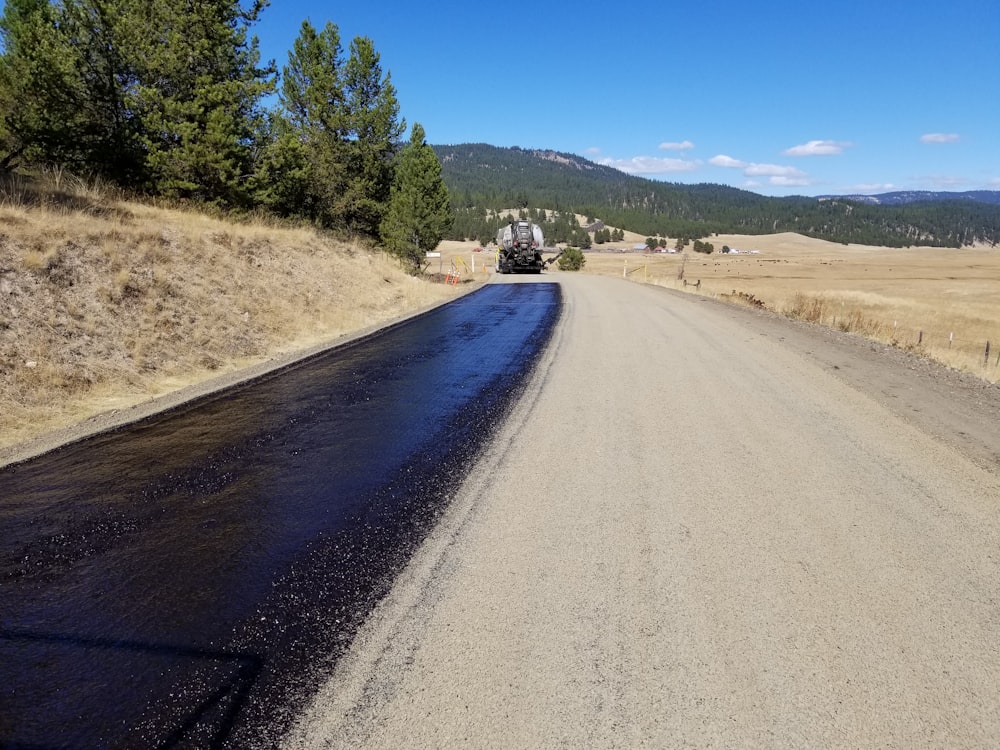 a truck driving down a road in the middle of a field