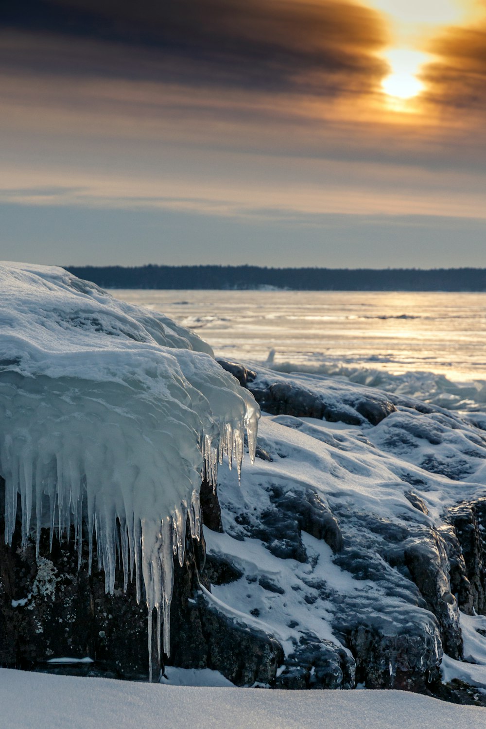 the sun is setting over the water and ice