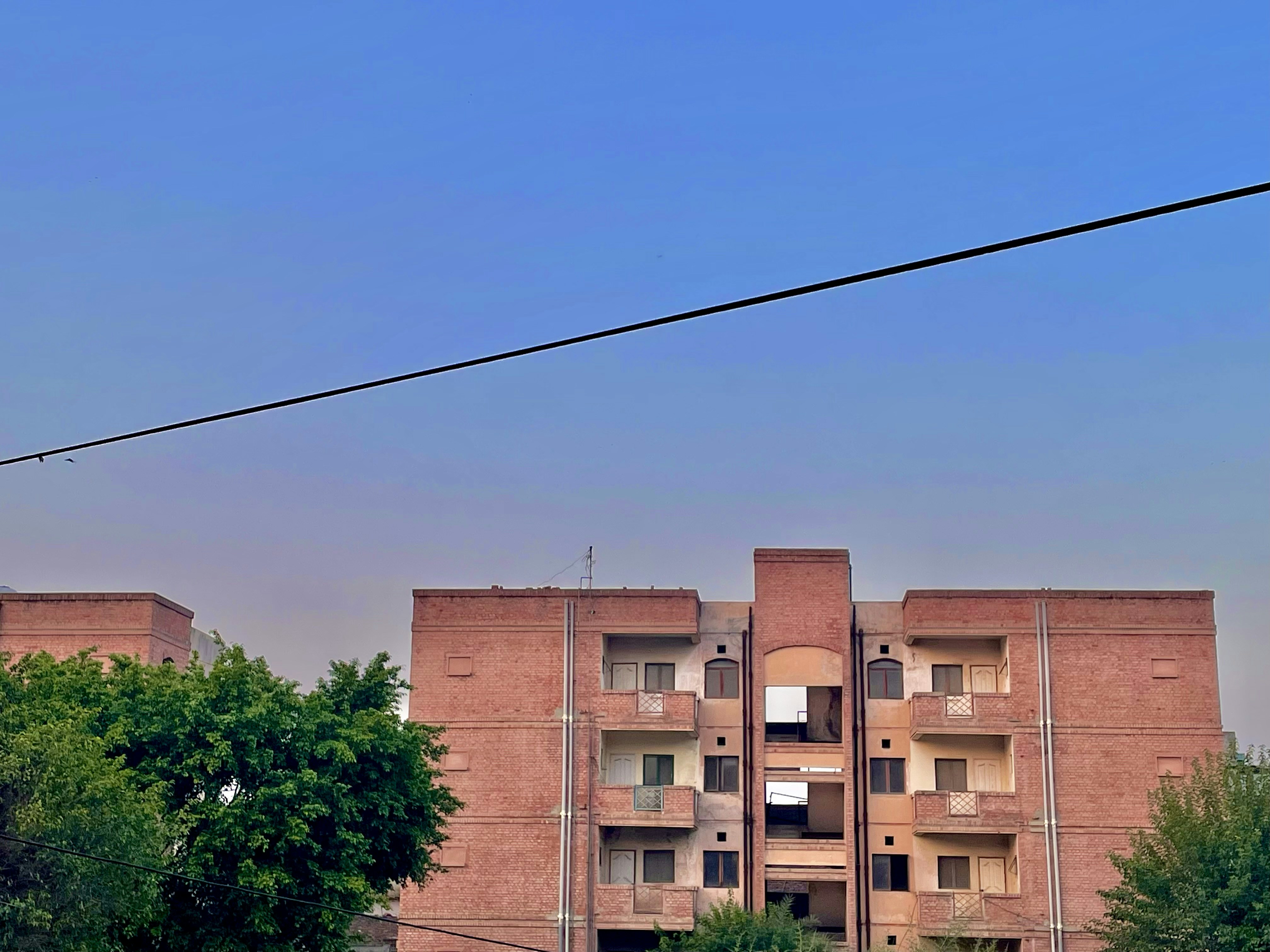 a tall brick building sitting next to a lush green forest