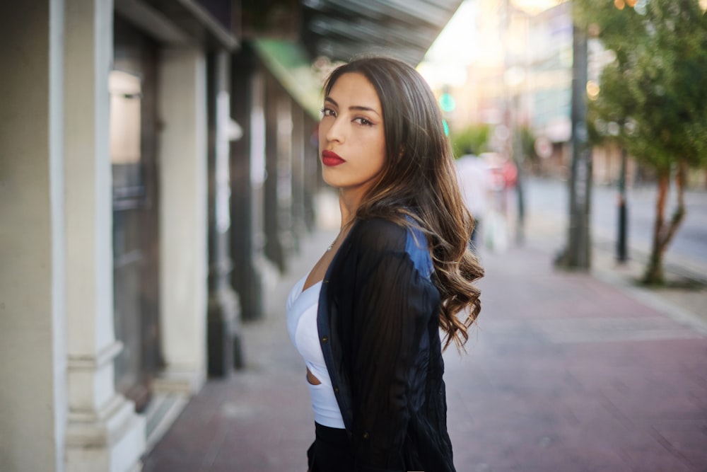 a woman standing on the side of a street next to a building