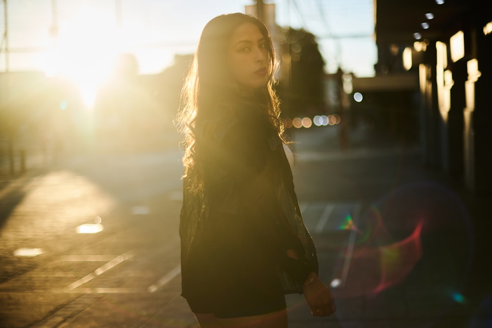 a woman standing on a sidewalk in the sun