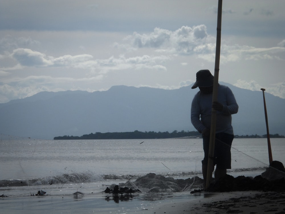 a man standing on a beach next to a body of water