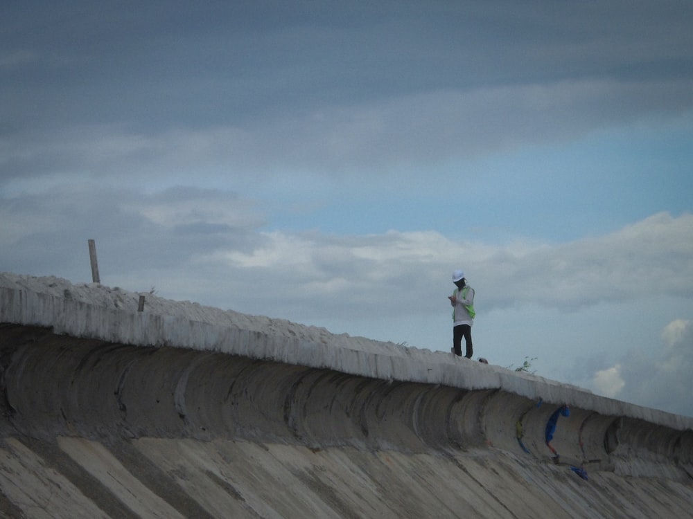 a man standing on top of a cement wall