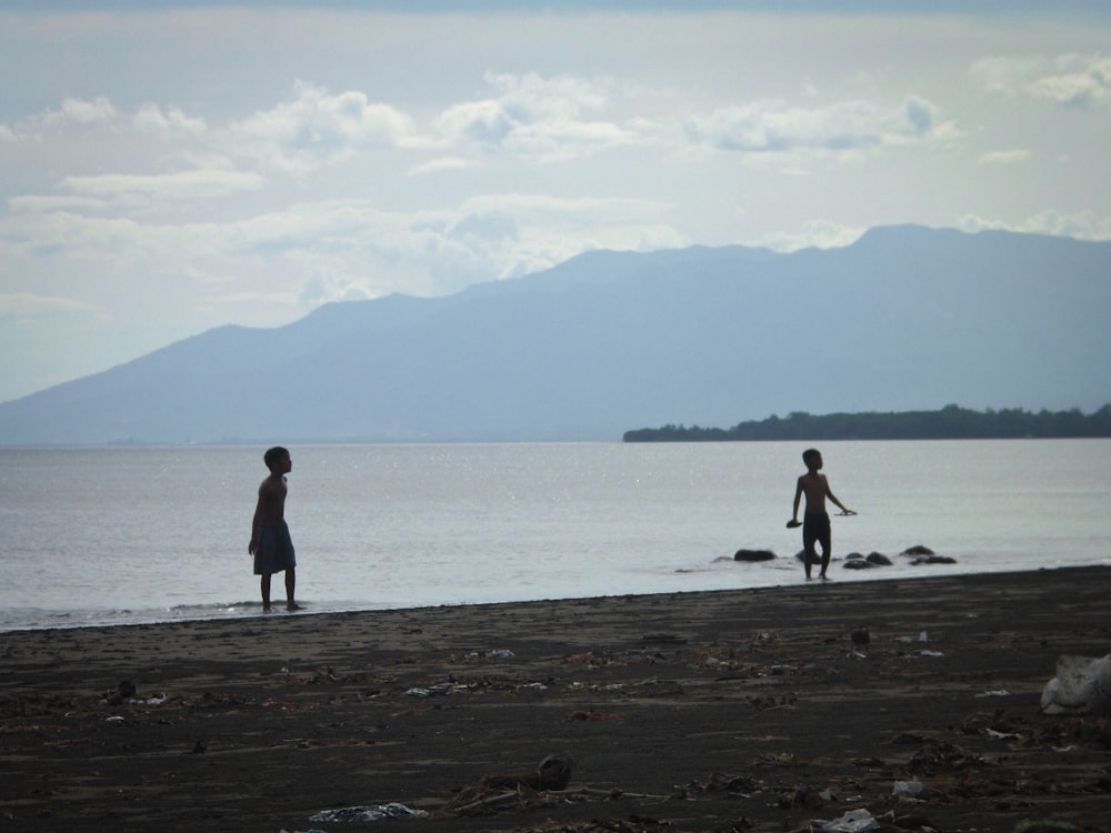 a couple of people standing on top of a beach