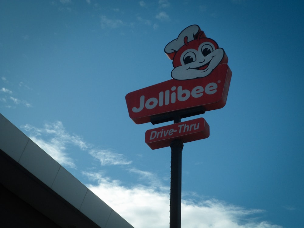 a jollibee drive thru sign with a sky background