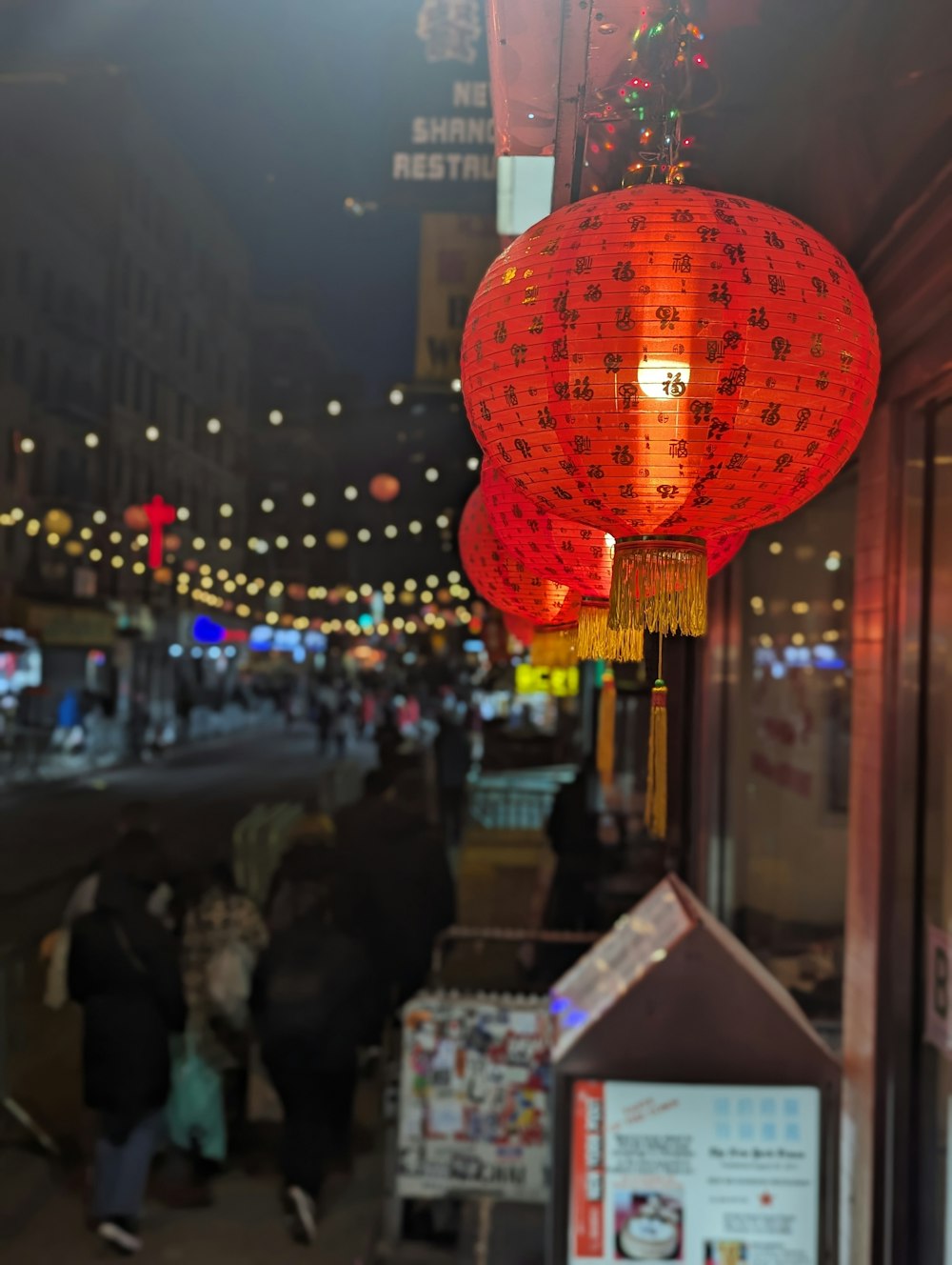 a red light hanging from a building next to a street